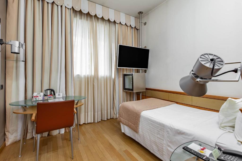Habitación de hotel con cama, escritorio y mesa. en HOTIDAY Hotel Milano Turro, en Milán