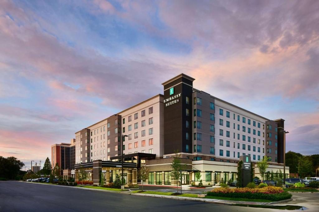 Embassy Suites By Hilton Atlanta Airport North في أتلانتا: عماره فندقيه فوقها ساعه