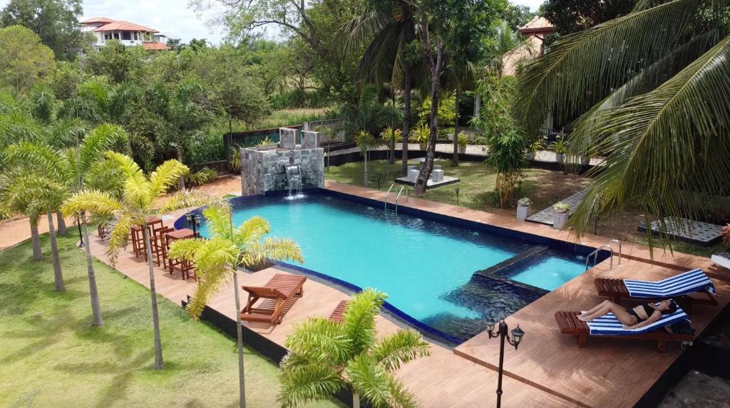 una vista aérea de una piscina con sillas y palmeras en White Land City Hotel en Dambulla