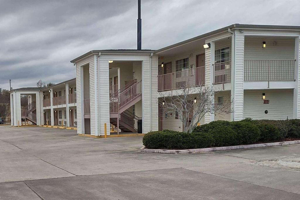 un gran edificio de apartamentos con balcones en un aparcamiento en Carom Inn a Travelodge by Wyndham Denham Springs-Baton Rouge en Denham Springs