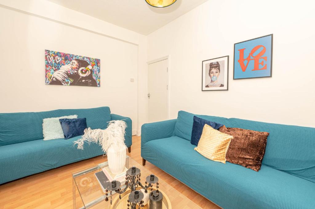 a living room with two blue couches and a glass table at Xtra Large 4 Bedroom House, near Excel, London City and 5 walk to Train Station in London