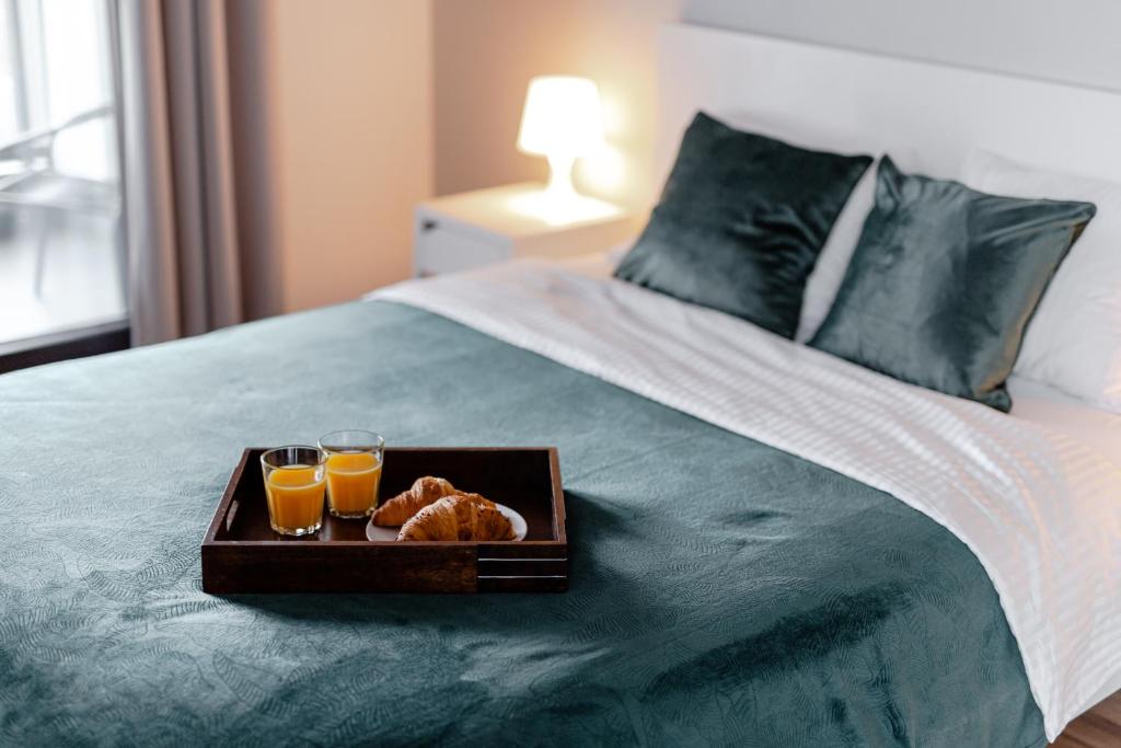 a tray of bread and two glasses of orange juice on a bed at City View Apartments in Warsaw