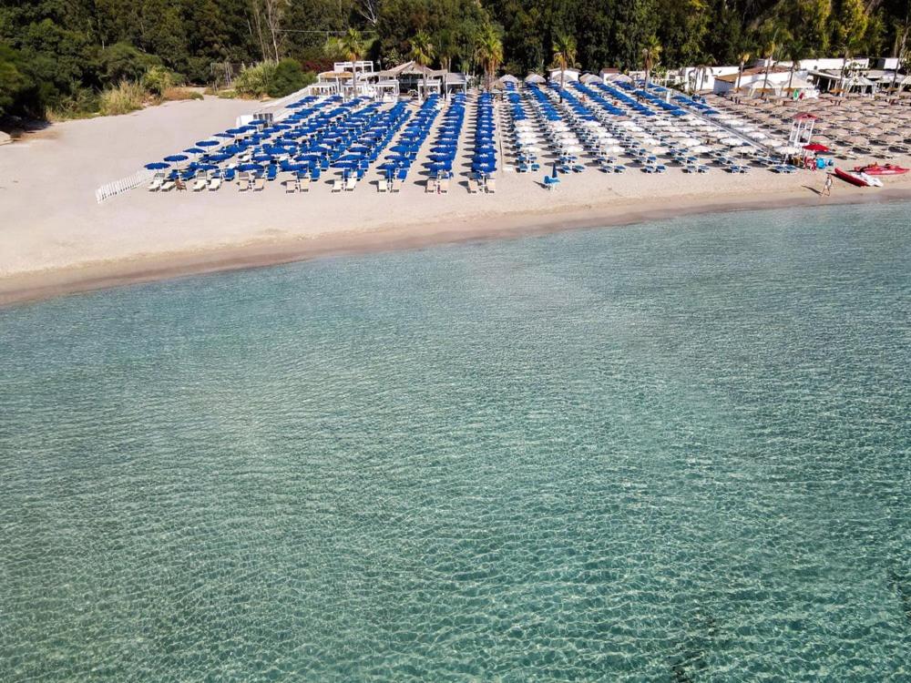 eine Luftansicht auf einen Strand mit Liegestühlen und Wasser in der Unterkunft Hotel Bulla Regia in Fontane Bianche