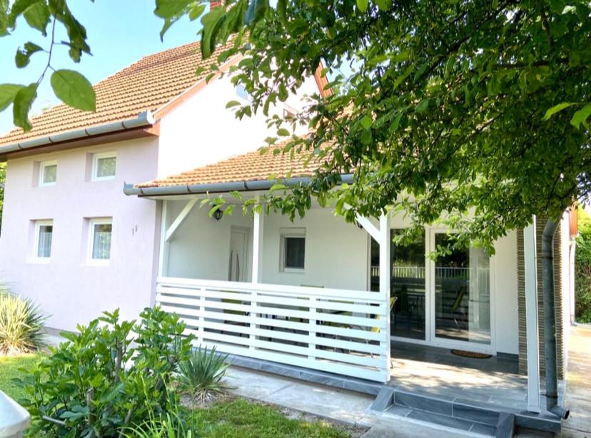 ein weißes Haus mit einem weißen Zaun davor in der Unterkunft Nika nyaraló jakuzzival in Balatonkeresztúr