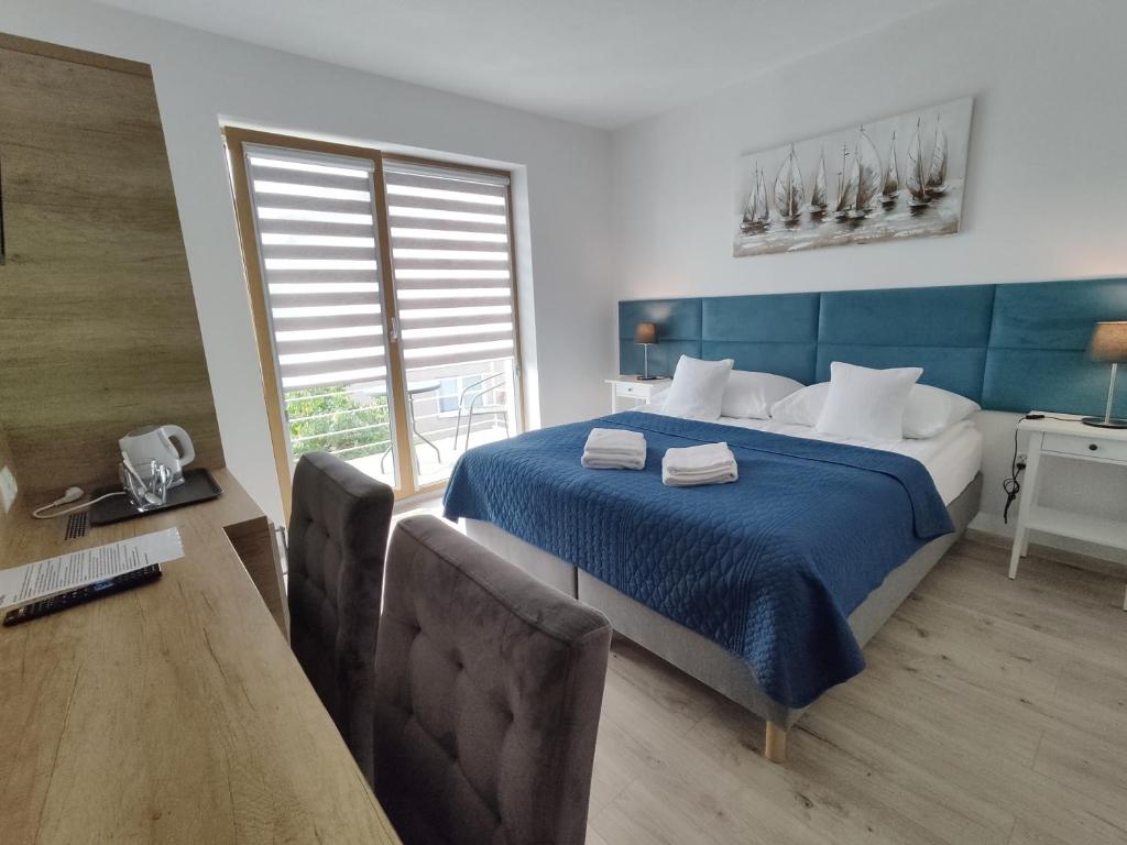 a bedroom with a blue bed with two chairs and a table at Willa M19 in Władysławowo