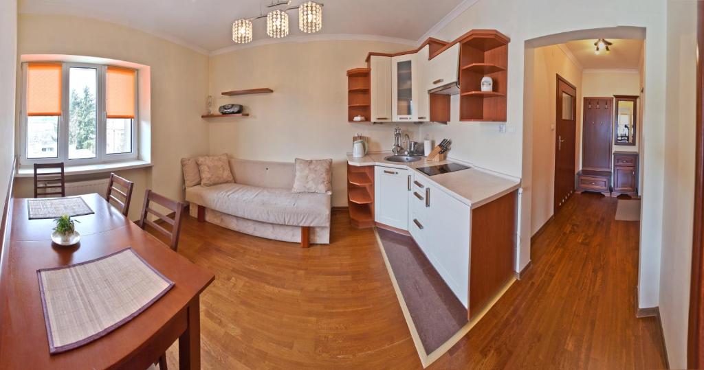 a kitchen and living room with a couch and a table at Apartamenty Sun & Snow Krynica Zdrój Pułaskiego in Krynica Zdrój