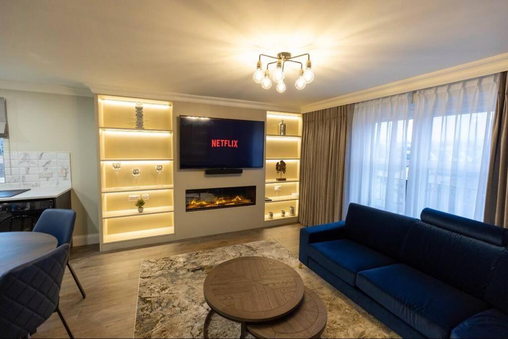 a living room with a blue couch and a fireplace at LUXURY TOWN CENTRE APARTMENT in Cookstown