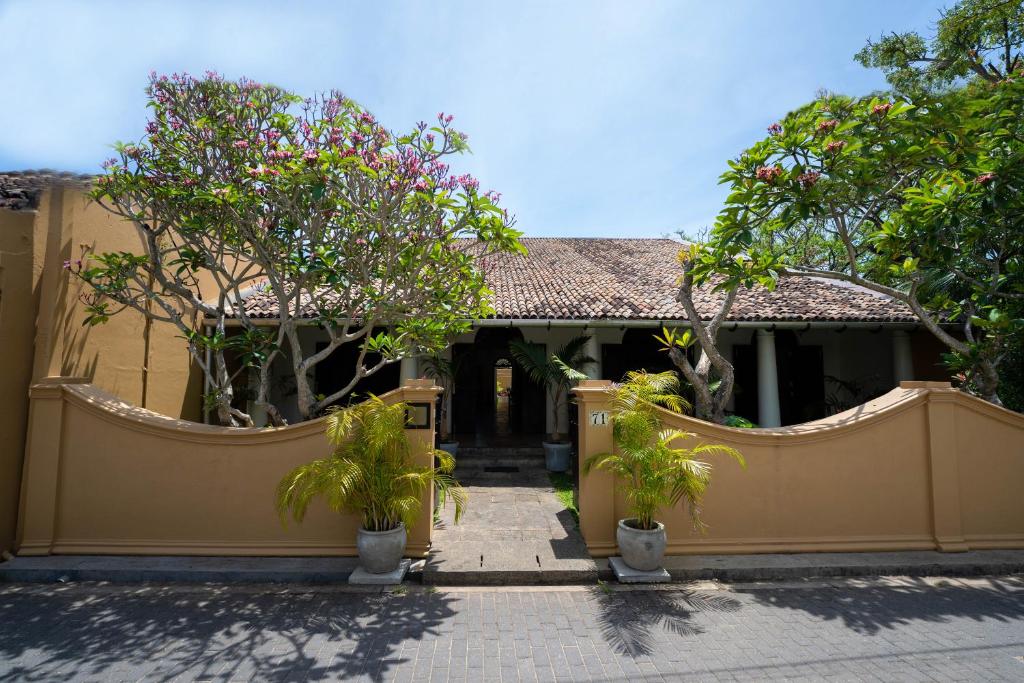 een huis met een hek en wat bomen en planten bij GALLE HERITAGE VILLA in Galle