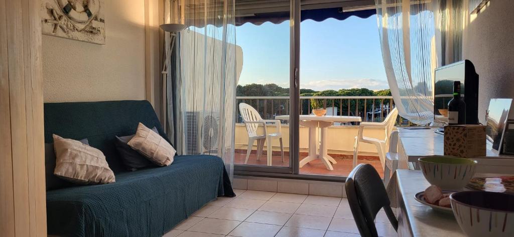 d'un salon avec un canapé et une vue sur un balcon. dans l'établissement Les Jardins 2 Port de Plaisance et piscine 2, au Grau-du-Roi