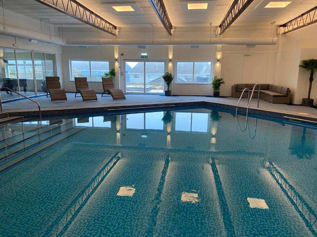 a large swimming pool with chairs in a building at Pentire Hotel in Newquay