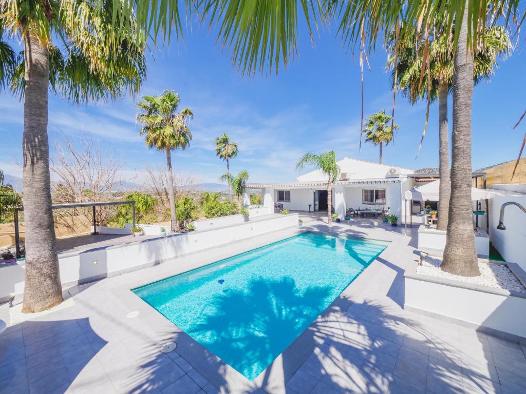 una piscina con palme di fronte a una casa di Cubo's Casa Flor High Privacy & Pool ad Alhaurín el Grande
