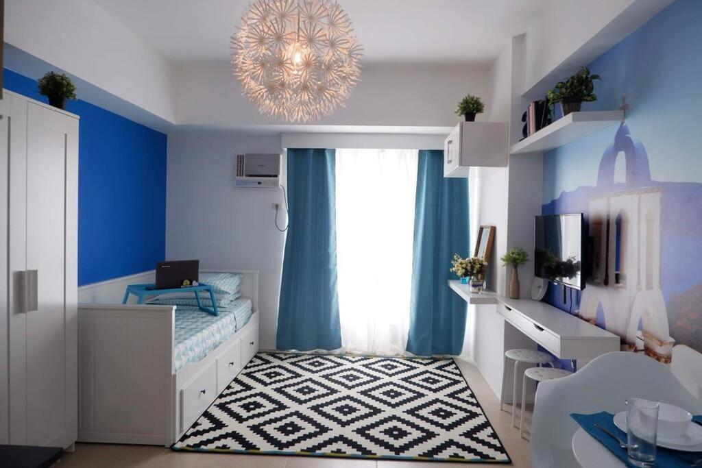 een slaapkamer met een bed met blauwe muren en een kroonluchter bij Santorini at Vertis North in Manilla