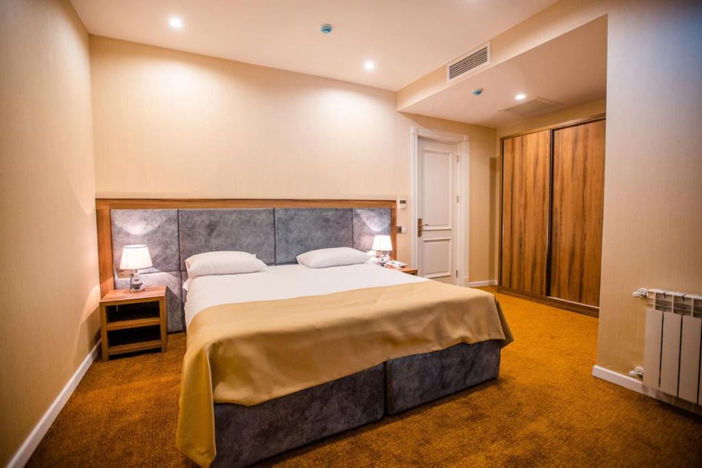 a bedroom with a large bed and two lamps on tables at Grand Midway Hotel in Baku