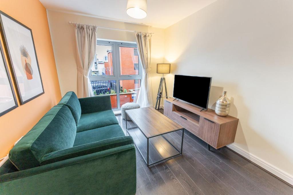 a living room with a green couch and a television at ALTIDO Modern flats in central Birmingham, next to business district in Birmingham