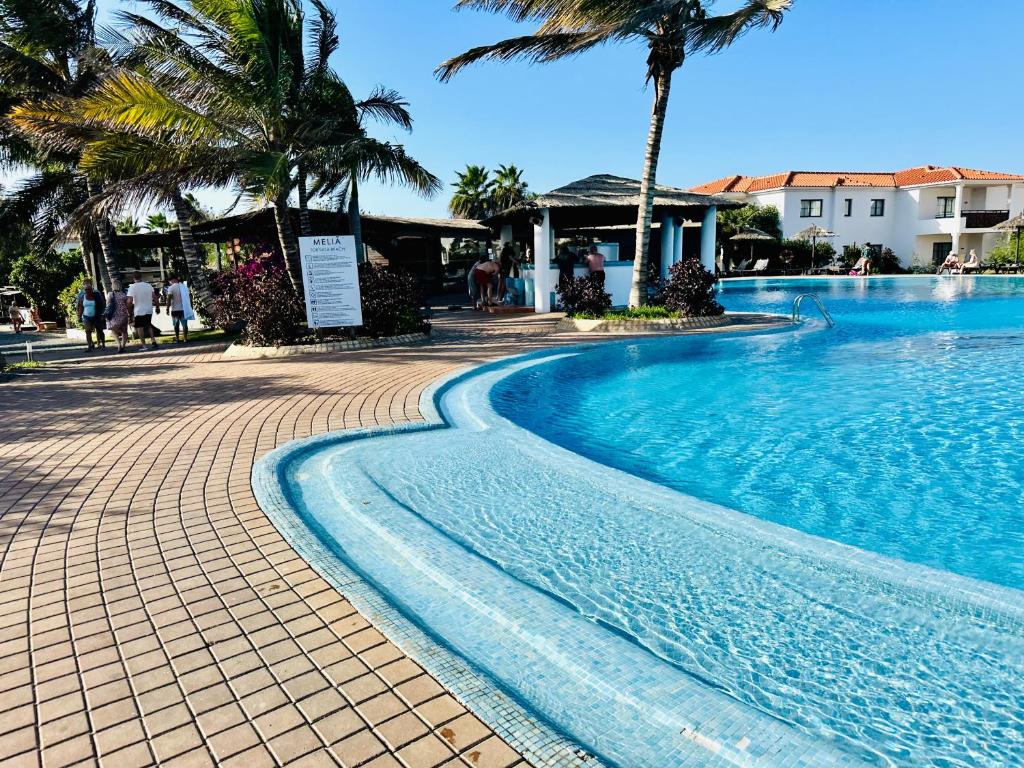 una piscina con palme accanto a un resort di Spacious Apartment @MeliaTortugaResort a Prainha