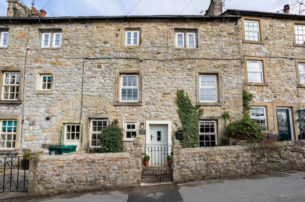 an old stone house with a white door at Primrose Cottage with Log Burner (Dog Friendly) in Settle