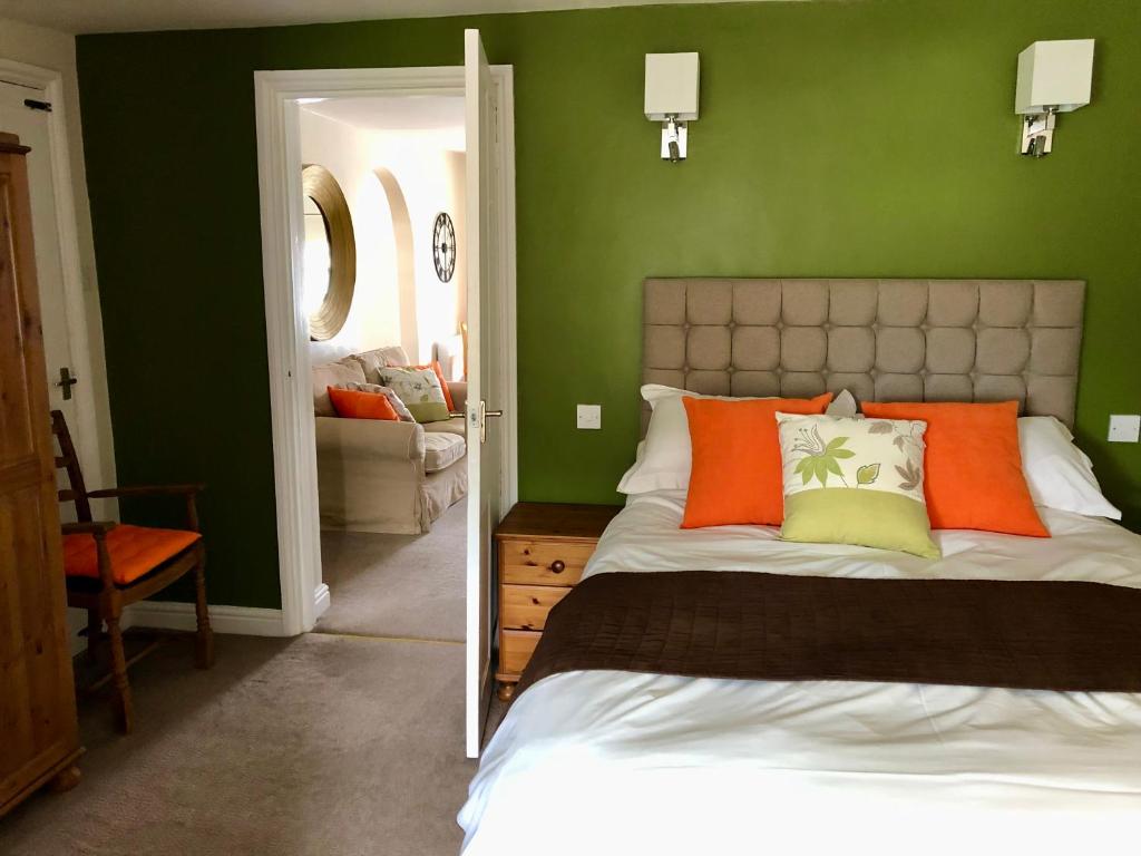 sypialnia z zielonymi ścianami i łóżkiem z pomarańczowymi poduszkami w obiekcie Fayvan Apartments w mieście Whitby