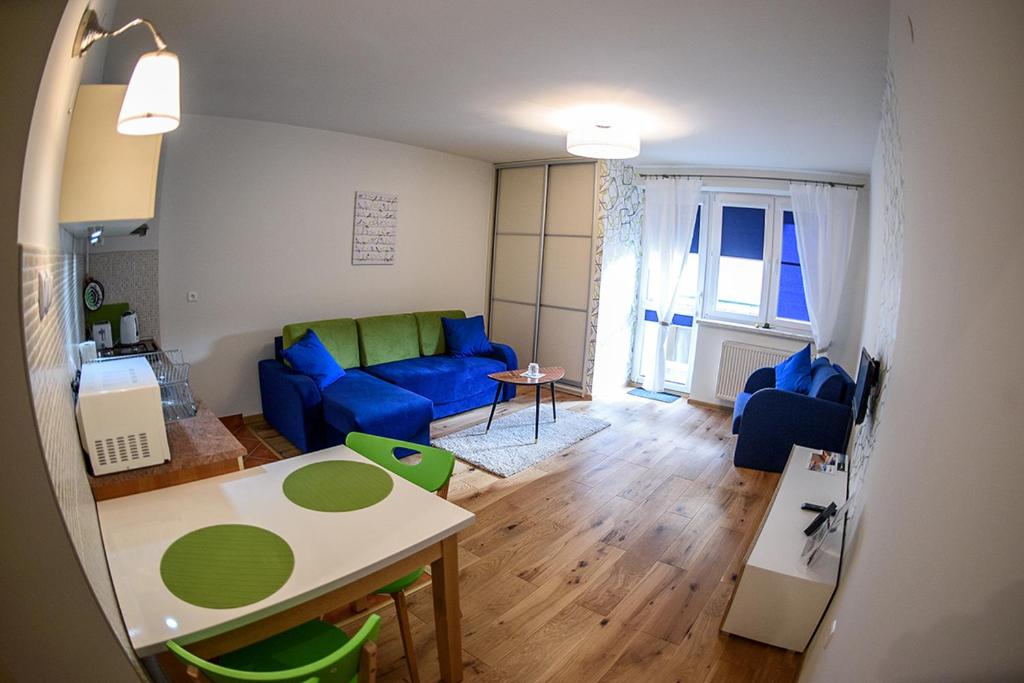a living room with a blue couch and a table at Apartamenty Sun & Snow Park Sportowy in Krynica Zdrój