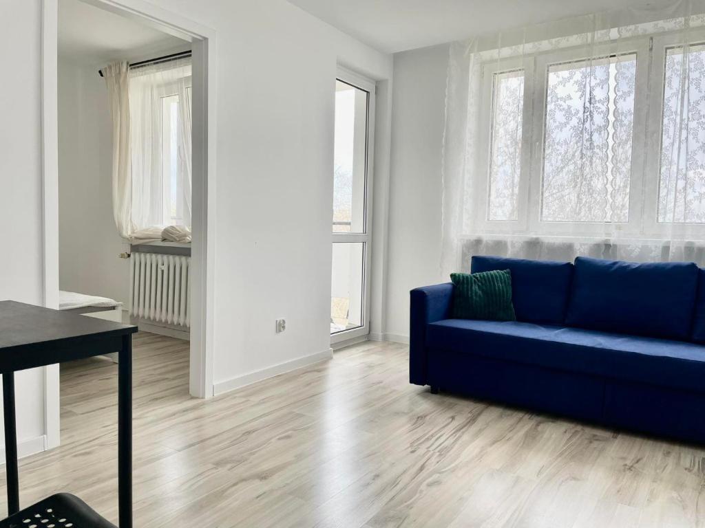 - un salon avec un canapé bleu et 2 fenêtres dans l'établissement 3K Popiełuszki 27, à Lublin