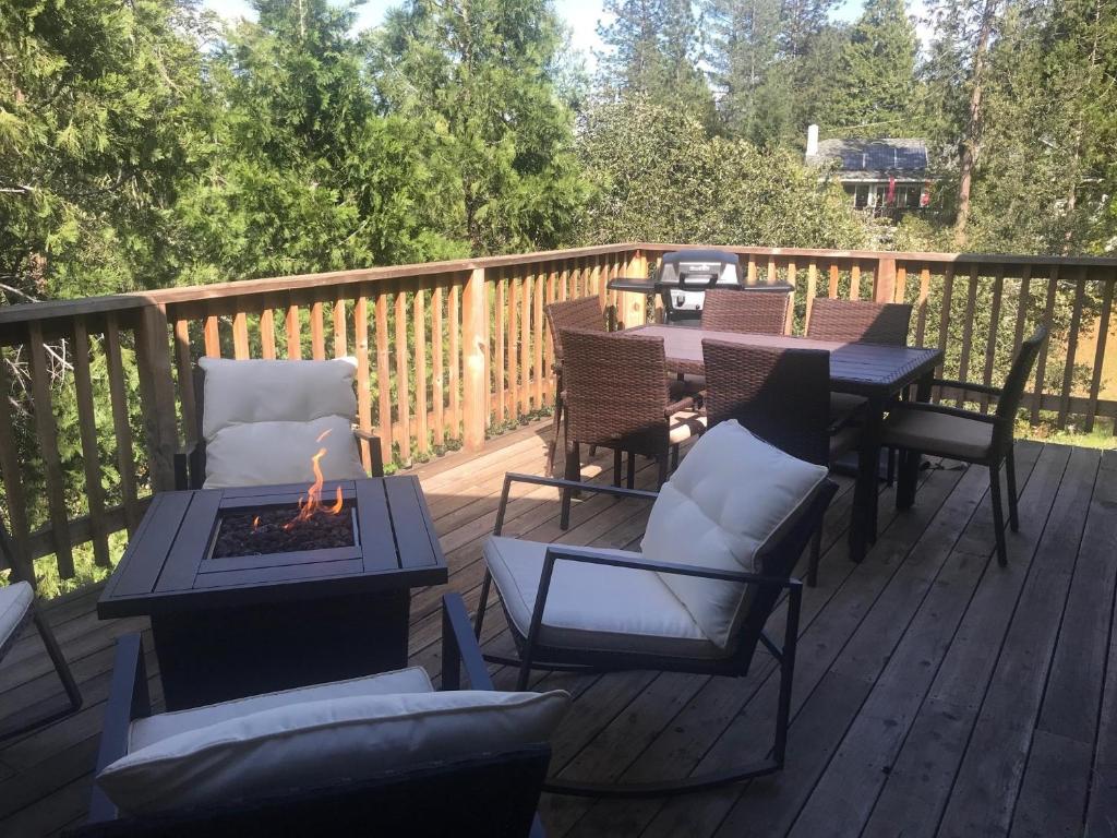 una terraza con sillas, mesas y una hoguera en Pet Friendly Grizzly Blair Lodge Cabin, en Groveland