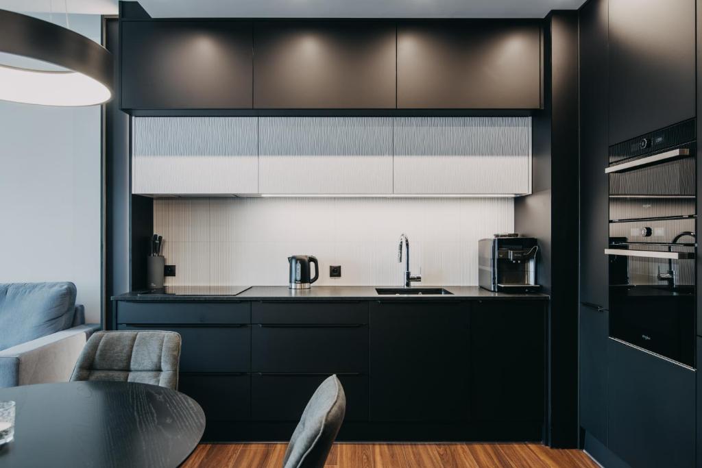uma cozinha com armários pretos e uma mesa em Black&White Bukowska18 B Apartment with Balcony and Garage em Poznań