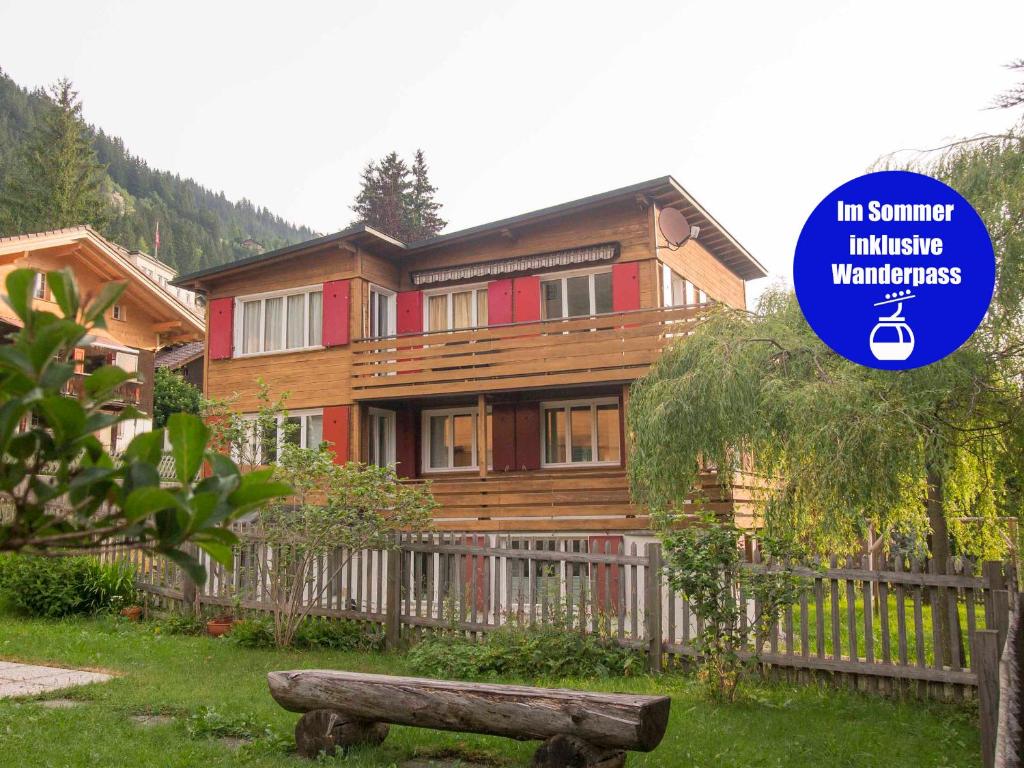 ein großes Holzhaus mit einem Zaun davor in der Unterkunft Chalet Azeno EG in Adelboden