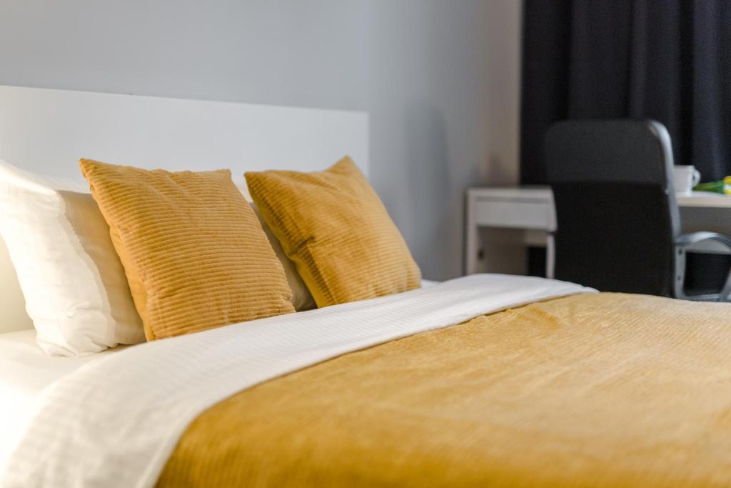 uma cama com almofadas amarelas e brancas em Warsaw City Apartments em Varósvia