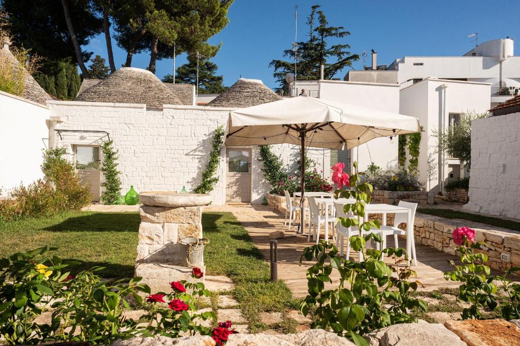 eine Terrasse mit Stühlen und einem Sonnenschirm vor einem Haus in der Unterkunft Trulli in corte in Alberobello