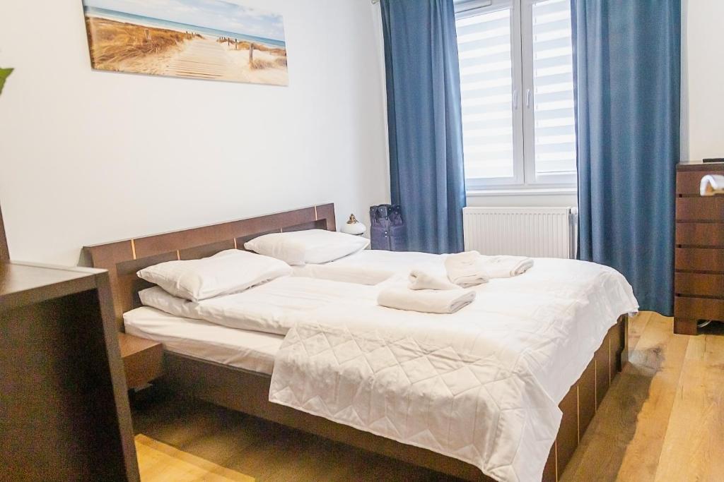 a bedroom with a bed with white sheets and pillows at Al-Dom Apartamenty Wiśniowy Ogród z garażem in Kołobrzeg