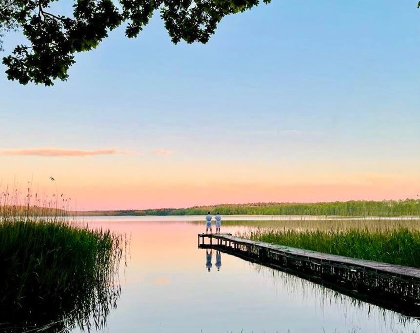 two people standing on a dock on a lake at Siedlisko Dziki Gil na Mazurach z prywatną plażą i SPA! in Ruś