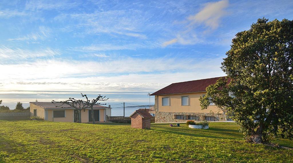 una casa en un patio de césped con un árbol en Casa con vistas al mar en Playa de Foxos, en Sanxenxo