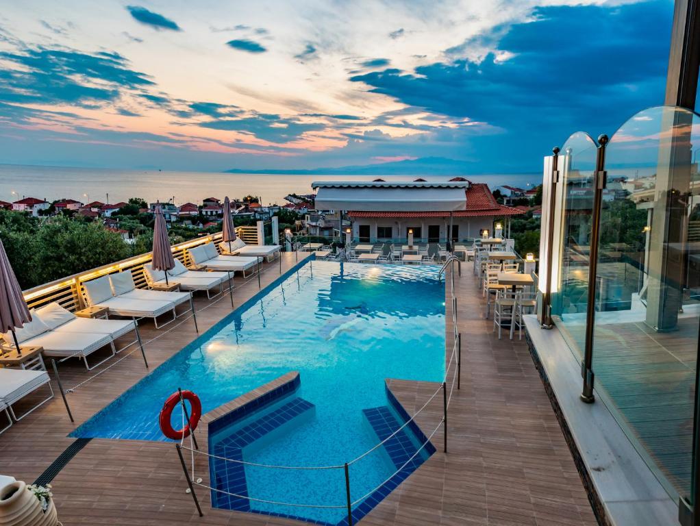 a pool on the roof of a building with lounge chairs at Anny Residences & Suites in Skala Kallirachis