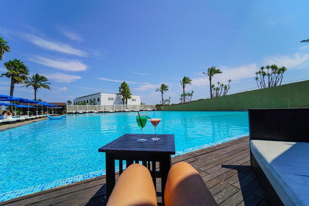 - une table avec un verre à côté de la piscine dans l'établissement Amareclub Baia Dei Turchi Resort - Adults Only, à Otrante