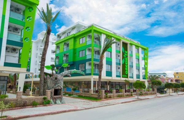 ein grünes Gebäude mit Palmen neben einer Straße in der Unterkunft Greenlife hotel in Alanya