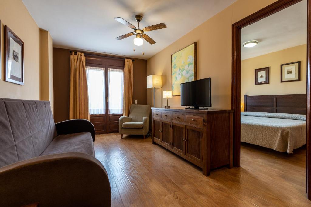 sypialnia z łóżkiem, telewizorem i kanapą w obiekcie Apartamentos La Trufa Negra w mieście Mora de Rubielos