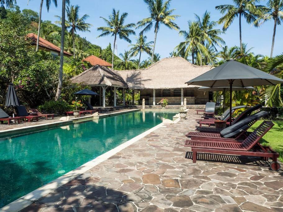 - une piscine avec des chaises longues et un parasol dans l'établissement Villa 7, Secret Garden, Kerandangan, near Senggigi, à Mataram