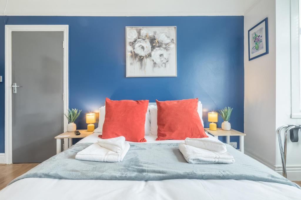 een blauwe slaapkamer met een groot bed met rode kussens bij Stylish Studio 4 with Kitchenette by CB Stays no minimum stays in Cambridge