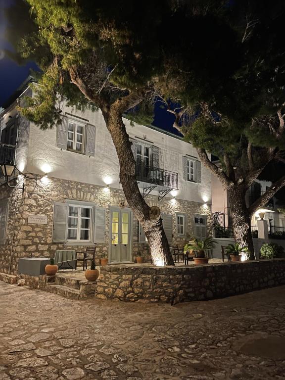 een stenen huis met een boom ervoor bij Piteoussa in Hydra