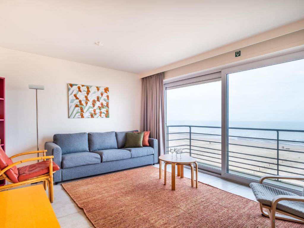 ein Wohnzimmer mit einem blauen Sofa und einem großen Fenster in der Unterkunft Attractive apartment in Koksijde with balcony in Koksijde