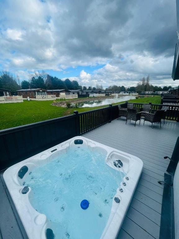 bañera de hidromasaje en una terraza con vistas al río en Belle Vue Lodge with Hot Tub, en York