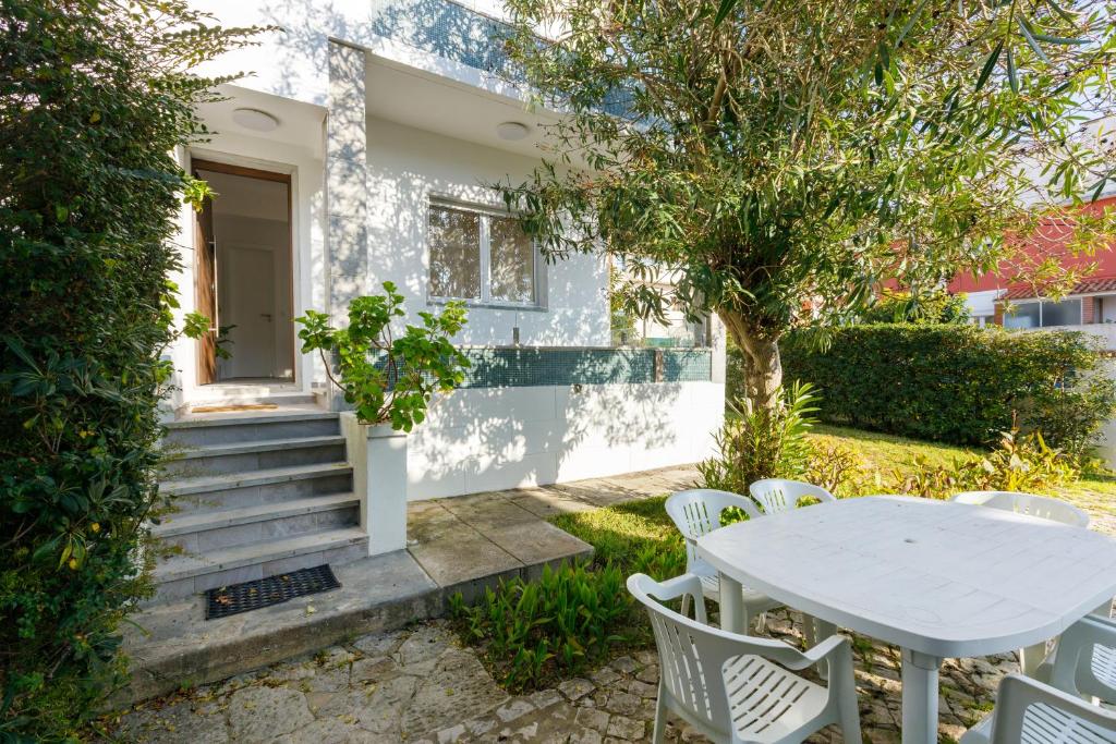a white table and chairs in front of a house at Villas Boas House Caparica in Costa da Caparica