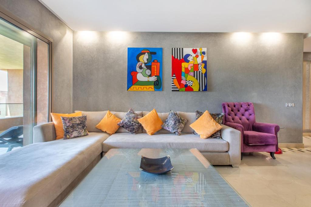 - un salon avec un canapé et deux peintures murales dans l'établissement Appartement XL Prestigia Topaze, à Marrakech