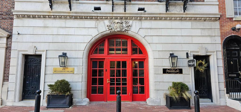 a red door on a white building with two windows at The Franklin on Rittenhouse, A Boutique Hotel in Philadelphia