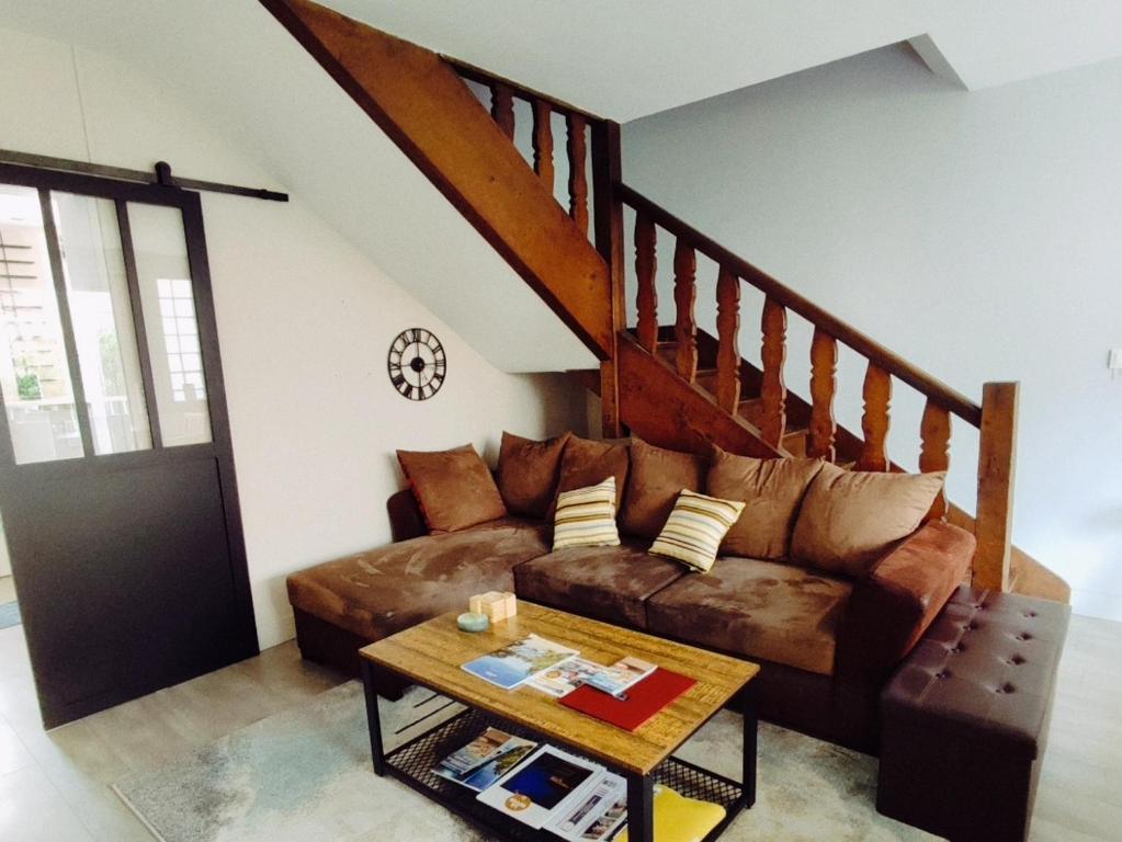 uma sala de estar com um sofá castanho e uma escada em Loueurdappart - Maison Calme Entre Mer et Commerces Tout à Pied em La Baule