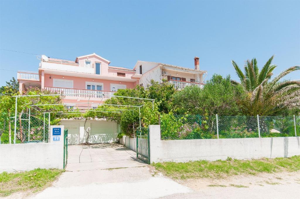 a pink house with a fence in front of it at Apartments Milan in Vlašići