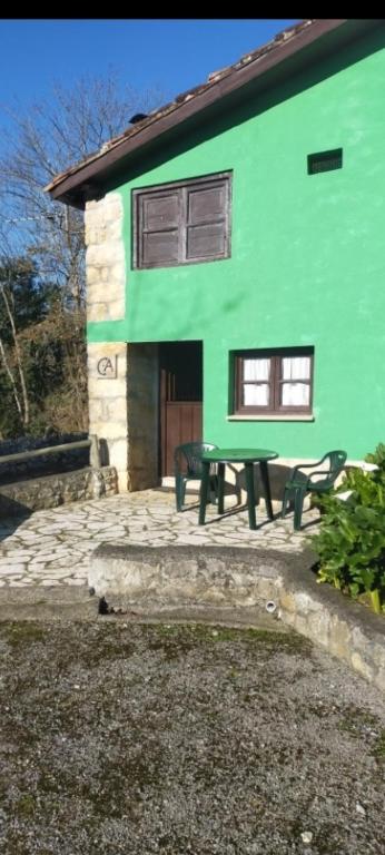 a green building with a picnic table in front of it at La casina de castiello in Arriondas