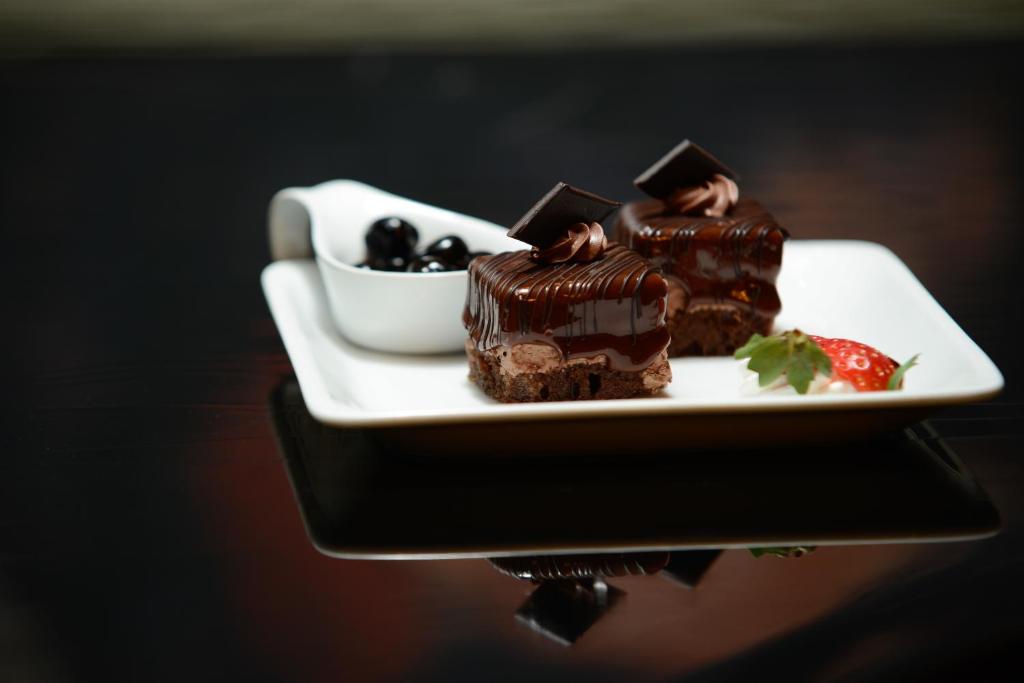 a plate with chocolate cakes and a bowl of berries at Grand Hotel Bucharest in Bucharest