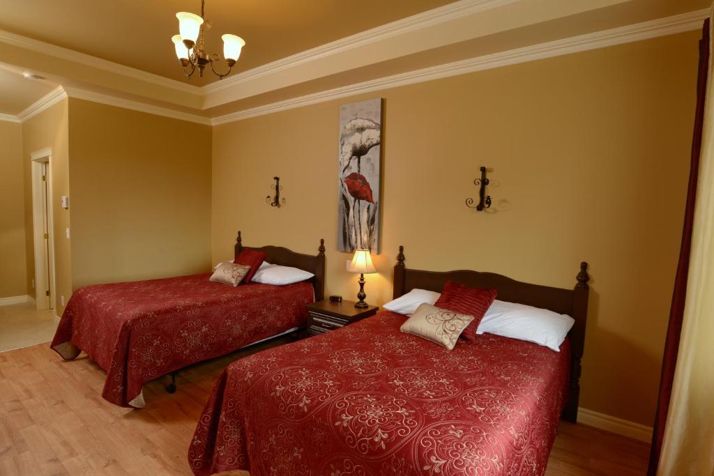 a bedroom with two beds with red comforters at Motel du Littoral in Rimouski
