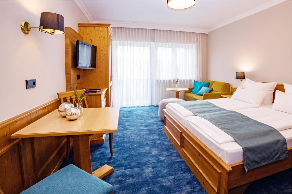 バート・フュッシンクにあるAppartementhaus Absmeierのベッドとリビングルームが備わるホテルルームです。