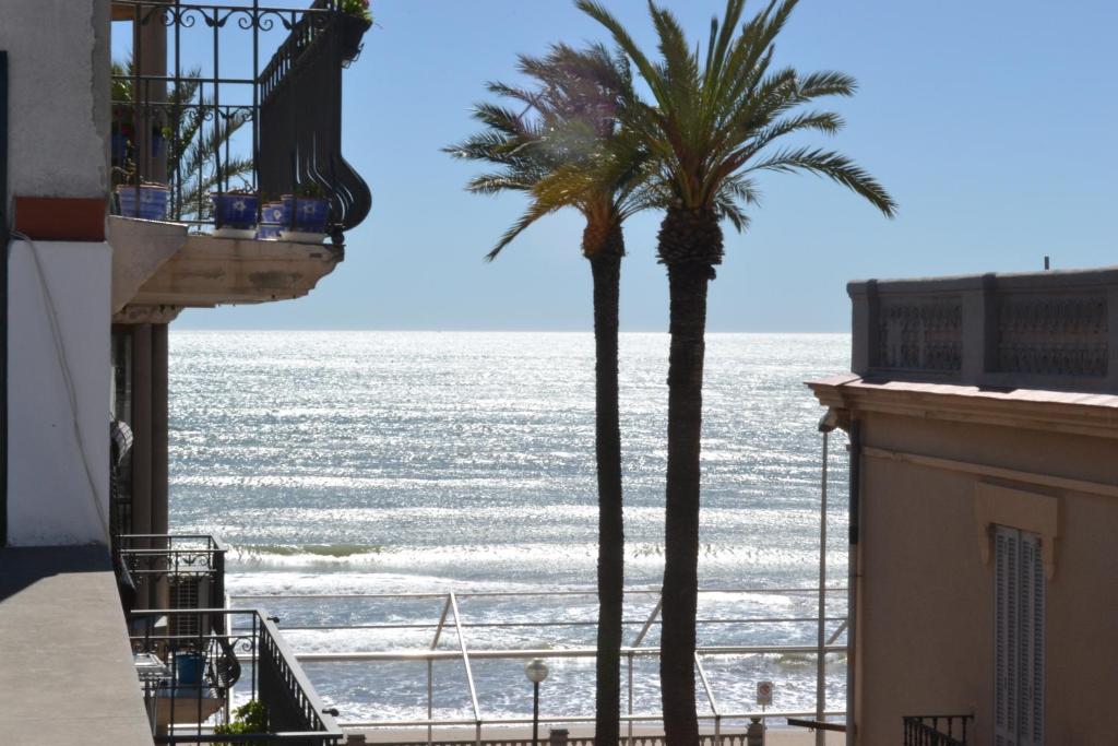 two palm trees on a balcony looking out at the ocean at Viva Sitges - Mayo Terrace in Sitges